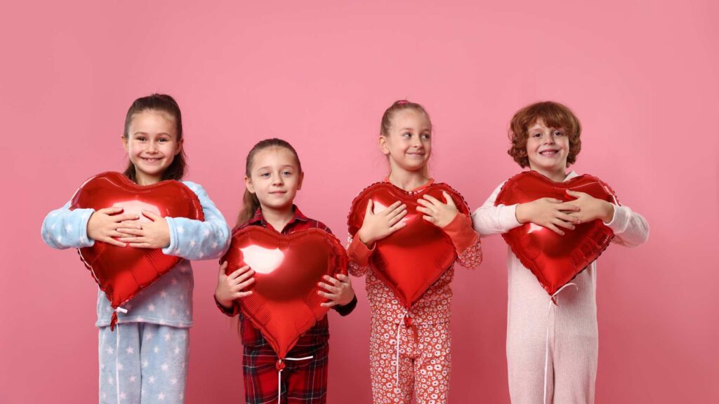 Niños abrazando corazones rojos, simbolizando el afecto en el Día de San Valentín y el autismo