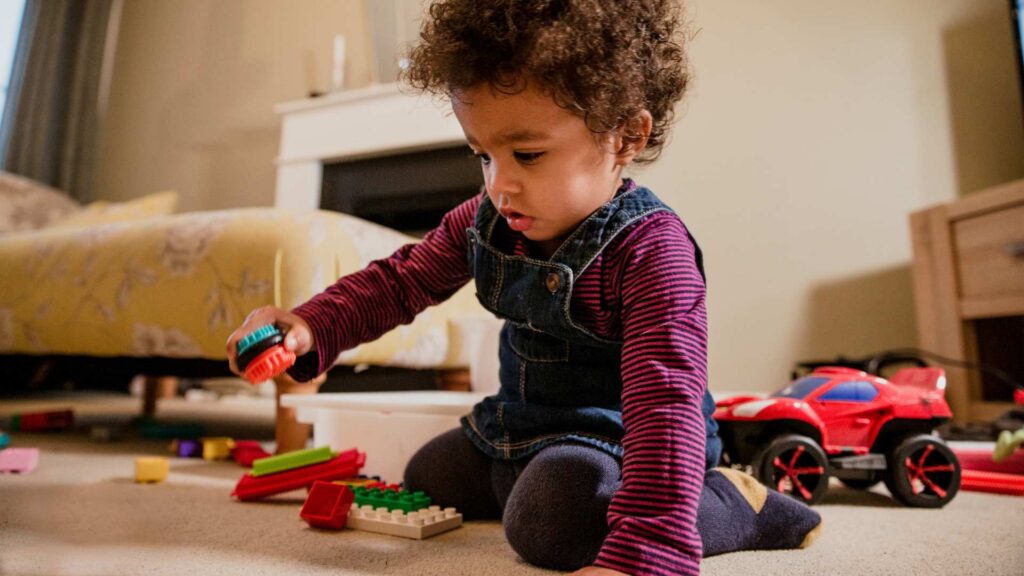Niño pequeño concentrado jugando con bloques en una habitación iluminada