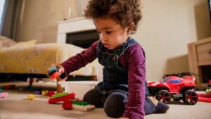 Niño pequeño concentrado jugando con bloques en una habitación iluminada