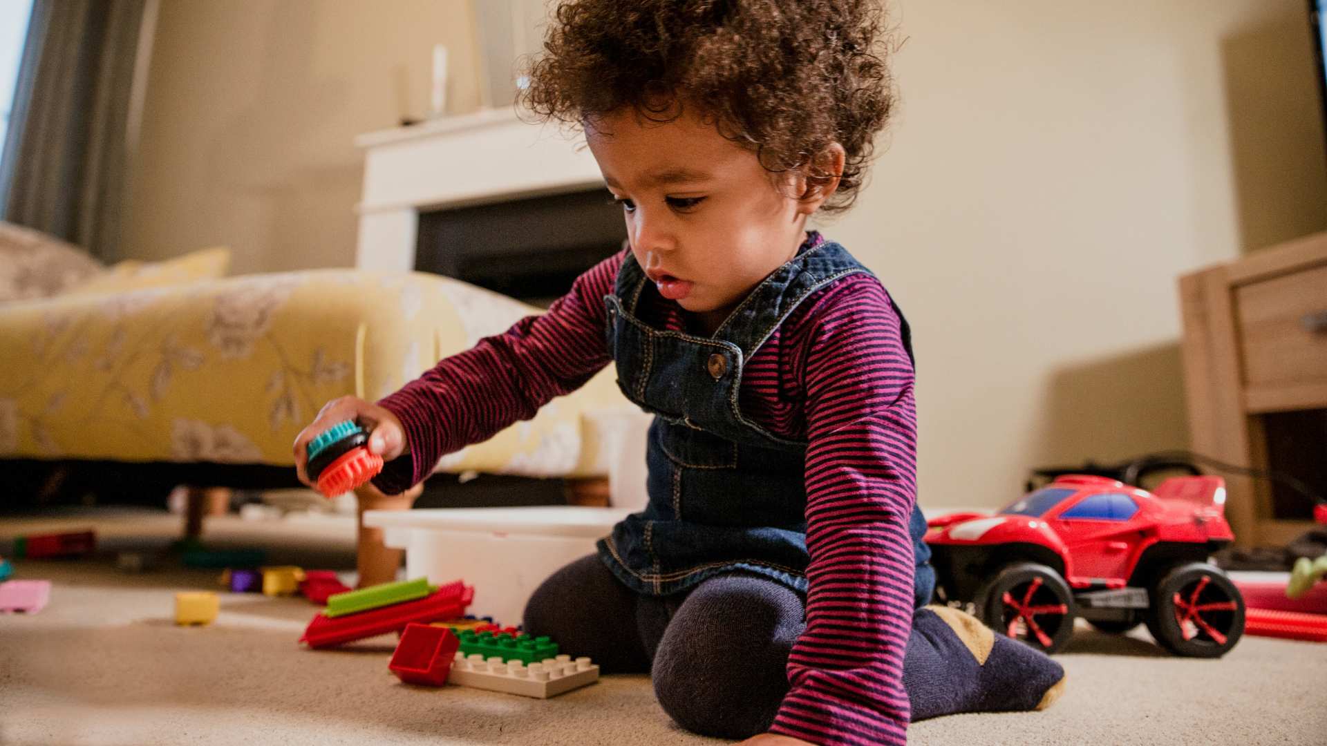 Niño pequeño concentrado jugando con bloques en una habitación iluminada