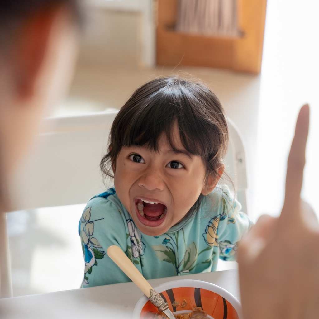 Niña pequeña con gesto intenso mientras come, imagen relacionada con señales tempranas de autismo