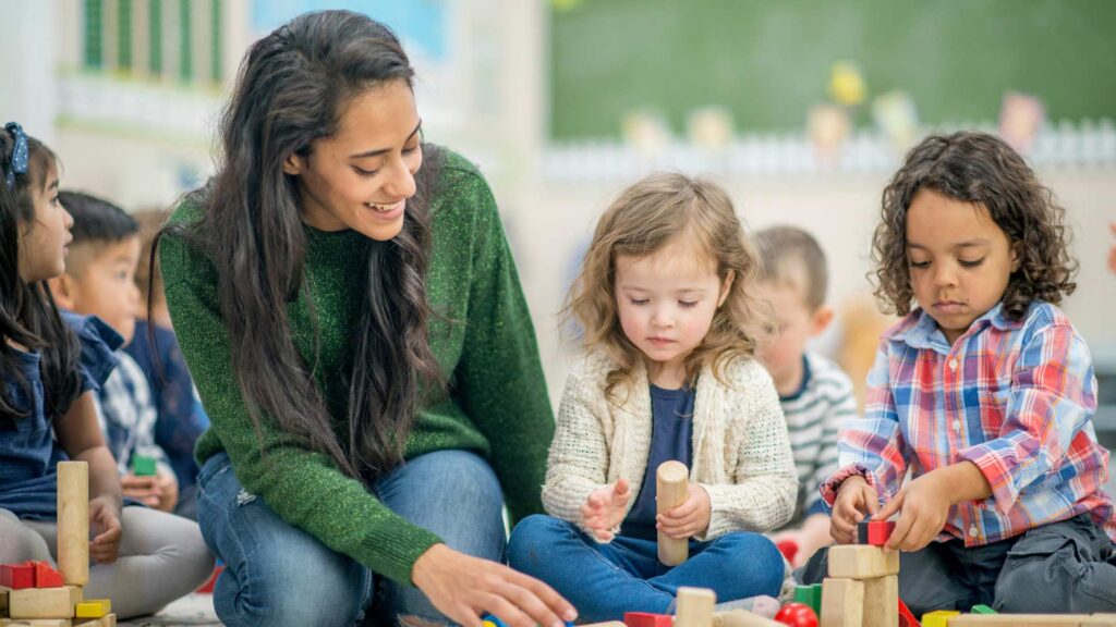 Terapeuta trabajando con niños pequeños durante una sesión de juego estructurado tipo ABA.