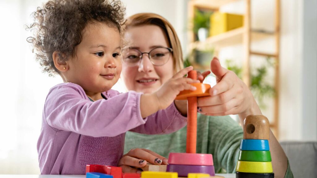 Cuidadora y niña realizando una actividad de juego guiada al iniciar la terapia ABA para niños pequeños