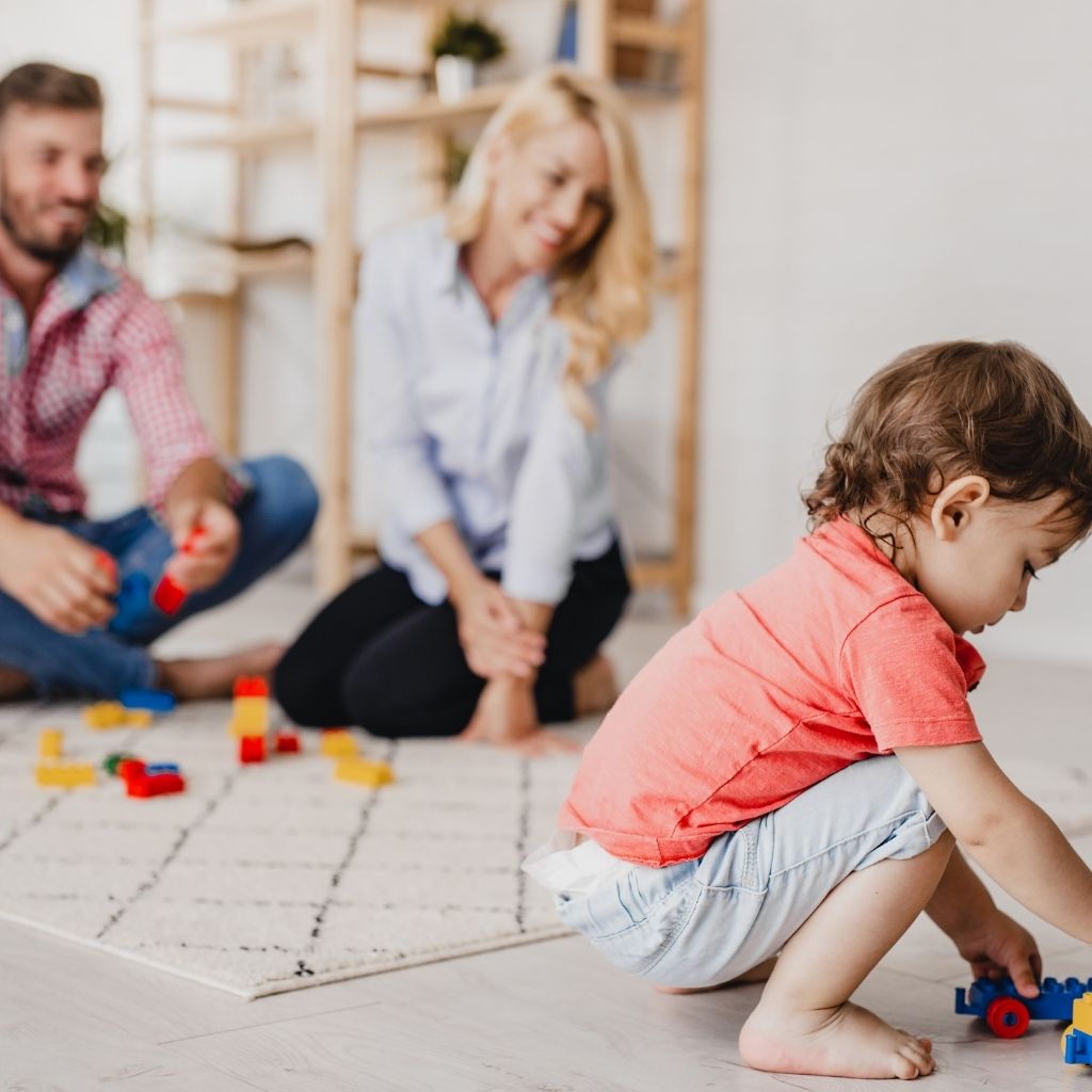 Niño jugando en casa mientras sus padres participan en la actividad